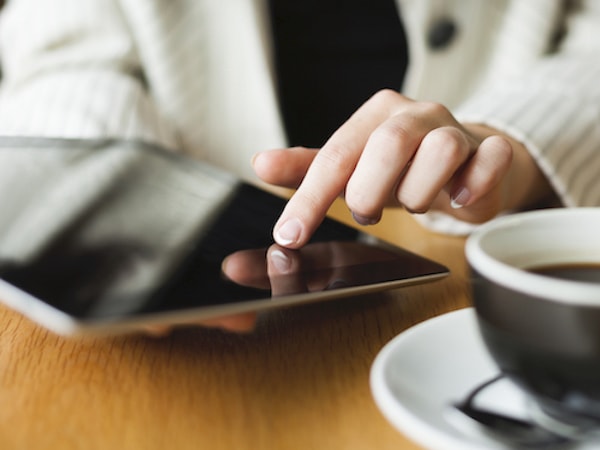 Close up of someone using a tablet next to a black coffee